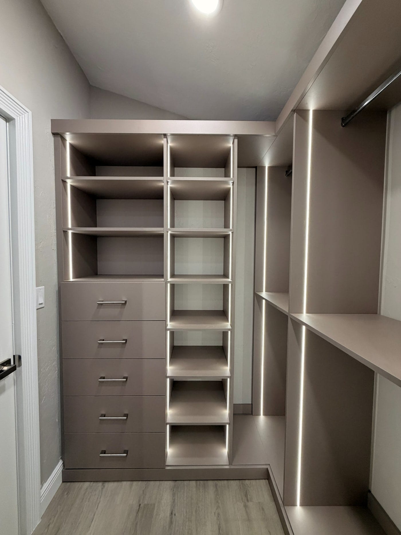 Taupe walk-in closet with drawers and strip lighting