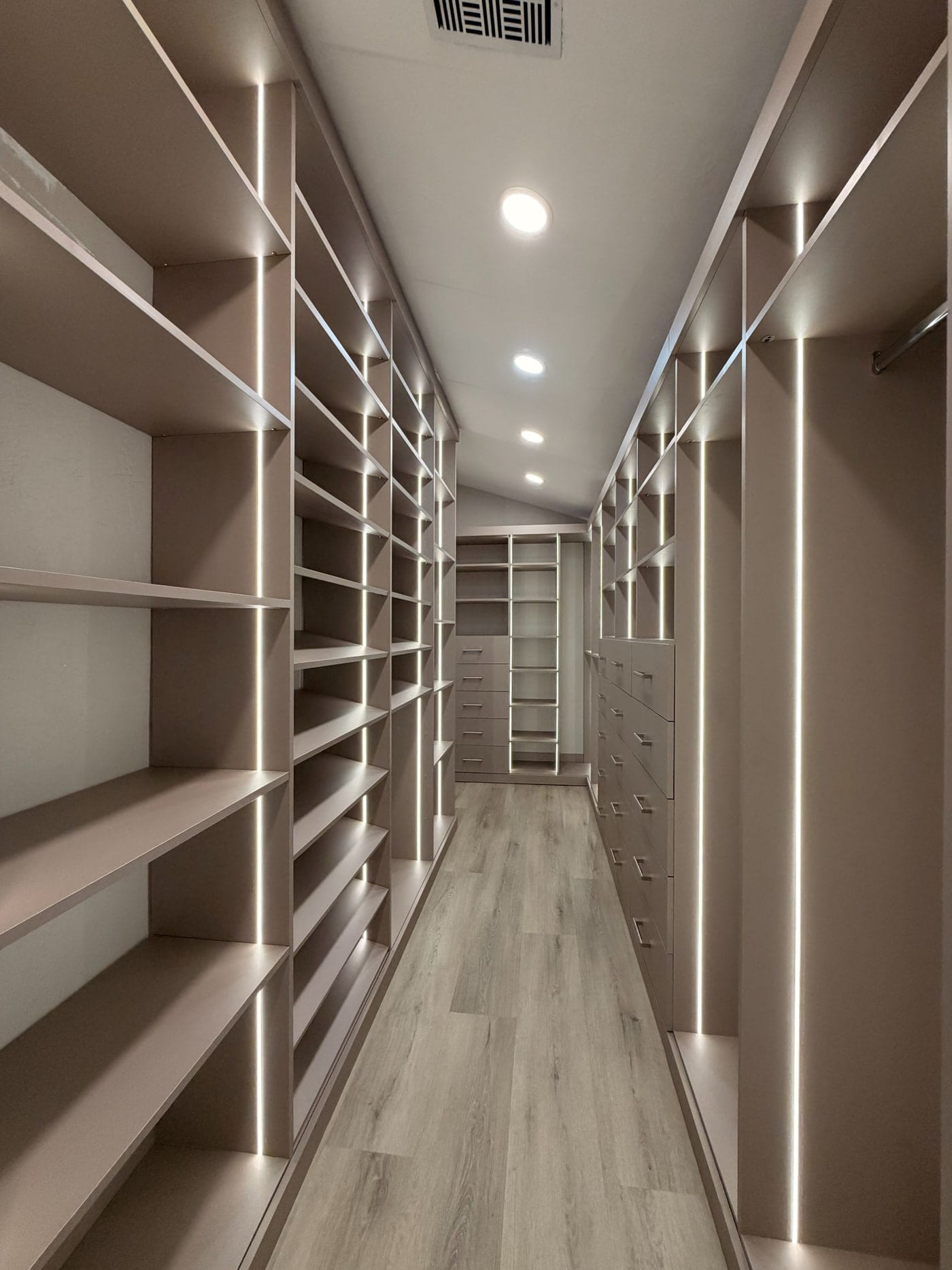 Long walk-in closet with full-height shelving down both walls