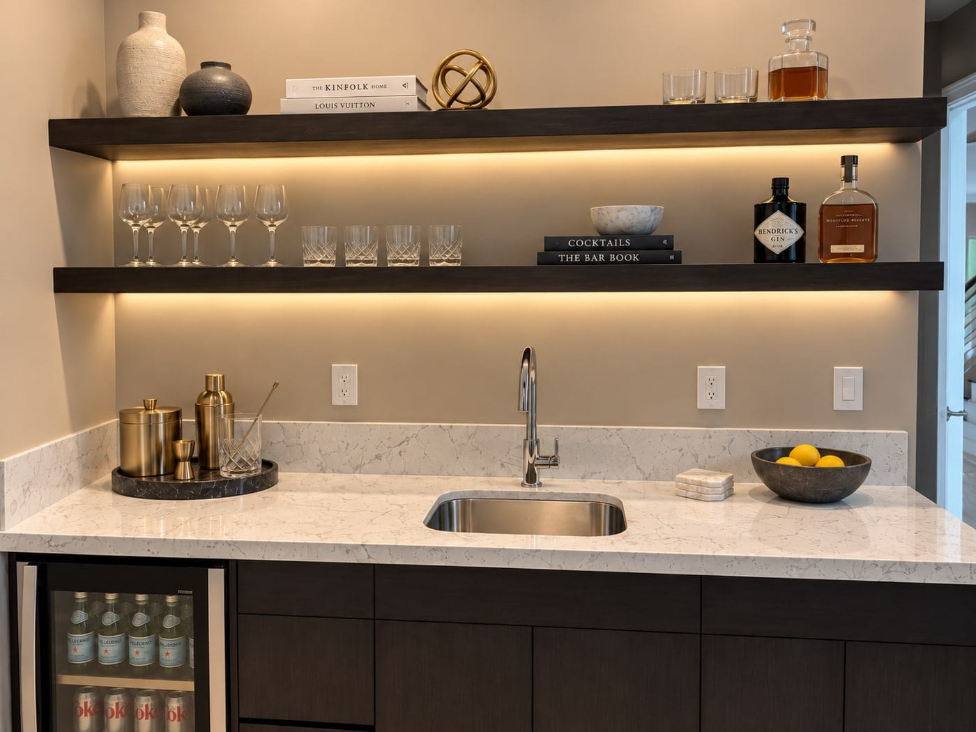 Wet bar with lit floating shelves over dark base cabinets