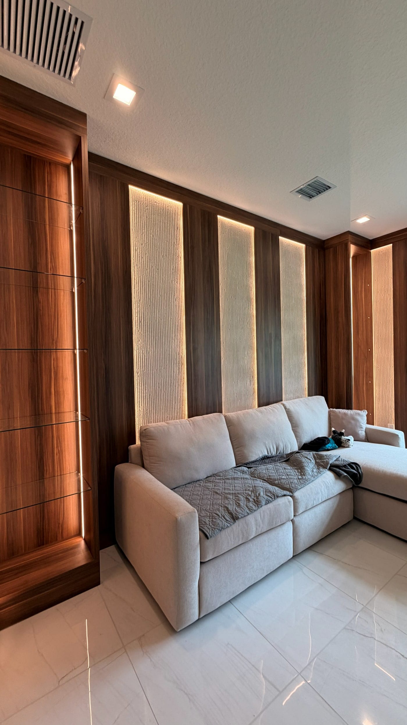 Living-room wall of warm wood panels with backlit inserts