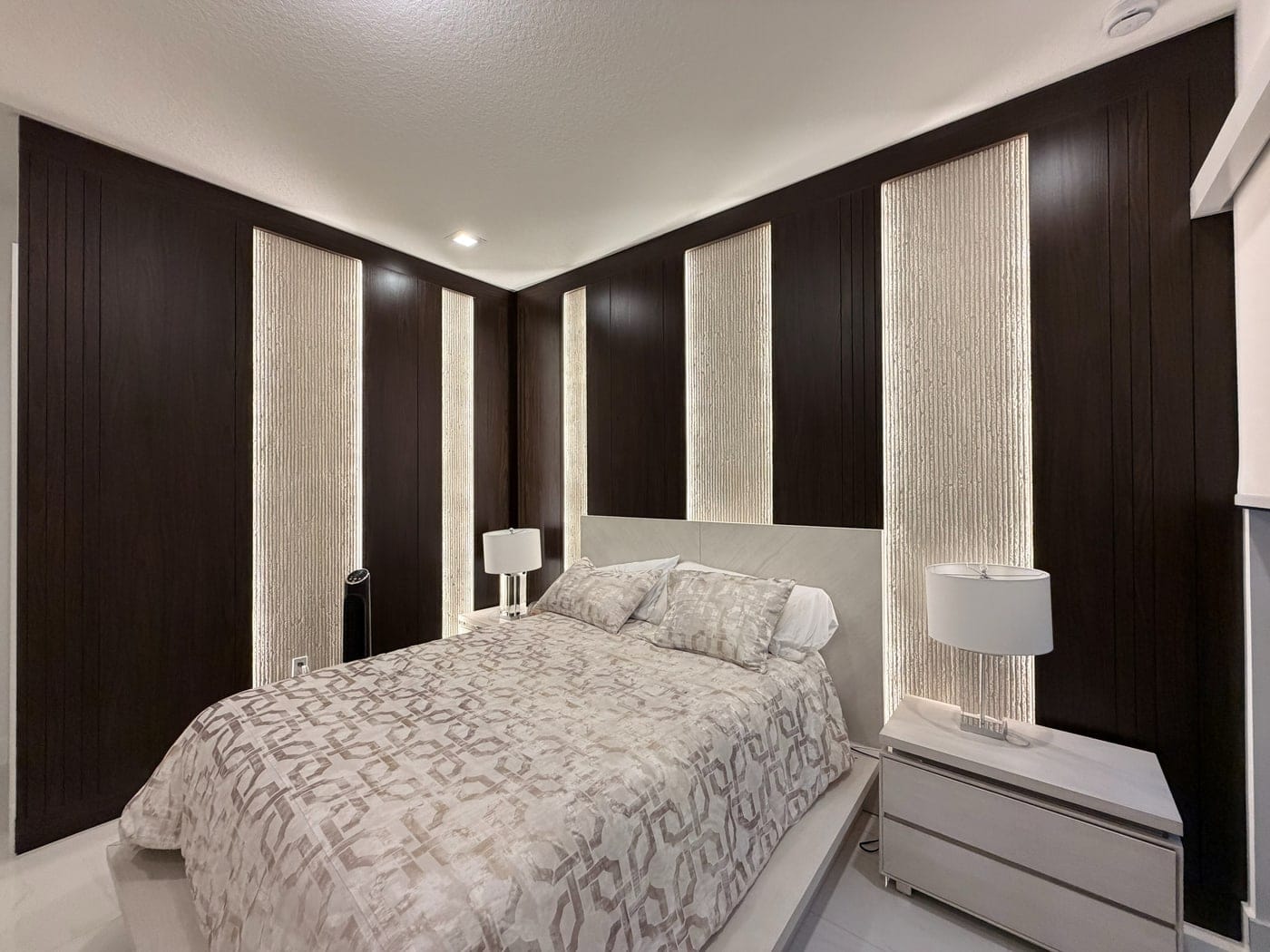 Bedroom wall of dark panels with backlit fluted inserts